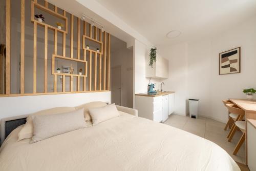 a bedroom with a white bed and a kitchen at Le Cocoon Studio 2 voyageurs in Arras