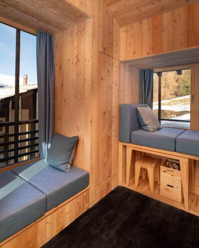 a room with two benches in a wooden cabin with windows at minipockethouse in Evolène