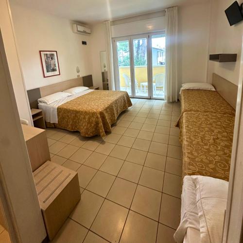 a hotel room with two beds and a balcony at Hotel Furga B&B in Cervia