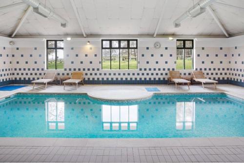 a large swimming pool with chairs and tables in a building at Gateway Mews - Serviced Apartments in Kegworth
