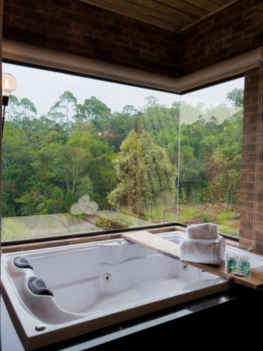 a bath tub in a room with a large window at Pousada Duas Marias in Nova Veneza