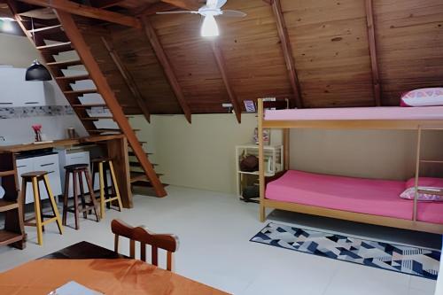 a room with bunk beds and a kitchen and a table at Chalé Primavera Rosa com piscina in Penha