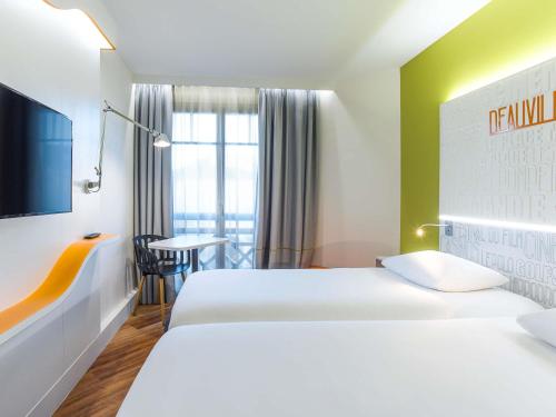a hotel room with two beds and a table at ibis Styles Deauville Centre in Deauville