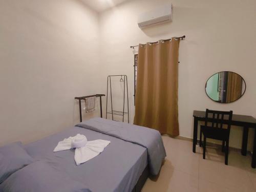 a bedroom with two beds and a table and a mirror at Seri Mersing Villa A in Mersing