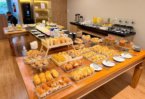 a buffet of pastries and other foods on a table at Life Residence in Belo Horizonte