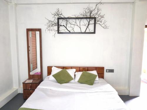 a bedroom with a bed with white sheets and green pillows at NANGRI Homestay in Pynursla