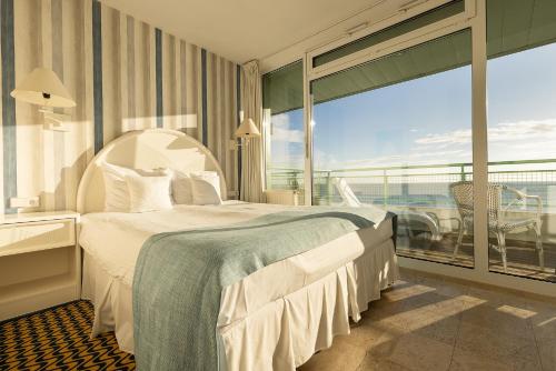 a bedroom with a large bed and a large window at Hotel Bryza Resort & Spa in Jurata