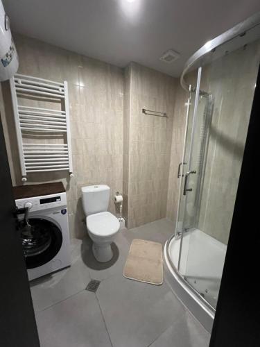 a bathroom with a toilet and a shower and a washing machine at Tribu Bakuriani in Bakuriani