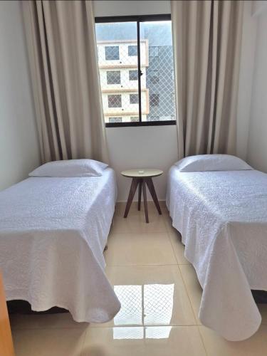 a bedroom with two beds and a table and a window at Apto 4 andar com vista incrível para piscina in Lucas do Rio Verde