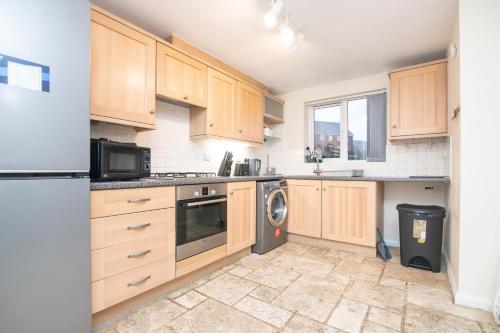 a kitchen with wooden cabinets and a washer and dryer at 5 bed house with free parking in quiet location in Wolverhampton