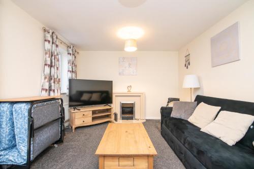 a living room with a black couch and a tv at 5 bed house with free parking in quiet location in Wolverhampton