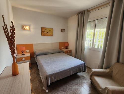 a bedroom with a bed and a couch and a window at Villa Xaloc piscine privée in Les tres Cales
