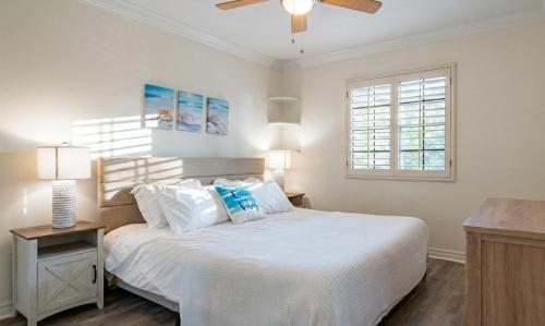 a bedroom with a white bed with a ceiling fan at Luxe 2-Story Oasis with Private Pool & Backyard in Laguna Niguel