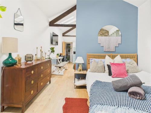 a bedroom with a bed and a dresser and a room at Stylish Central Famouth Studio with Parking | WiFi | in Falmouth