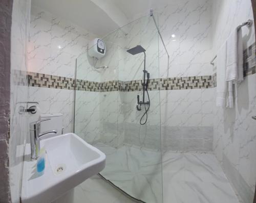 a white bathroom with a shower and a sink at ROSES REGENCY HOTEL AND SUITES in Abuja