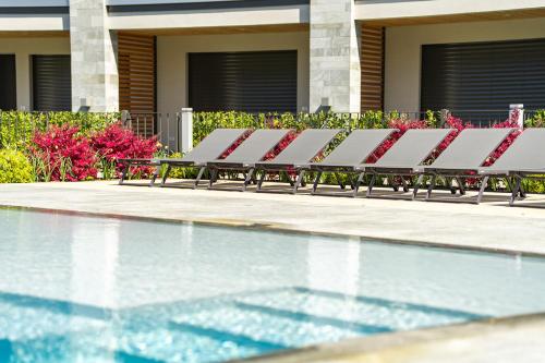 a row of lounge chairs next to a swimming pool at Lago Dorato Luxury Apartments - Lake Como View in Colico