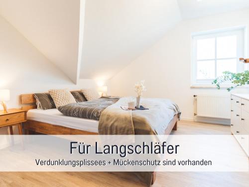 a white bedroom with a bed and a window at Huus Binnensee OG2 - Dachwohnung mit Wasserblick - Lesesessel & WLAN - Für Paare - Ruhige Lage - Südstrand 5 Min mit Rad in Fehmarn