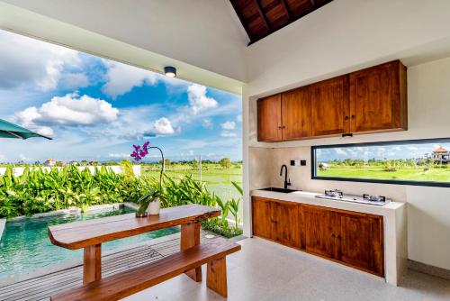 a kitchen with a table and a large window at Svadarma Bali Villa by Dhananjaya Hospitality in Darmasaba