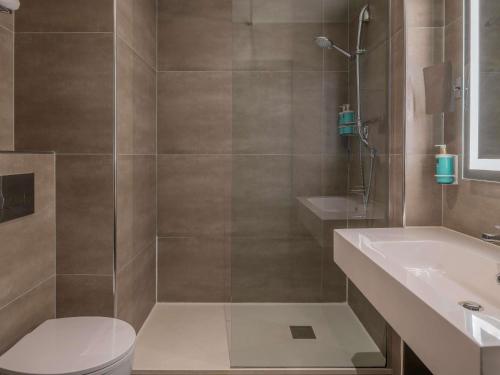 a bathroom with a shower and a toilet and a sink at Novotel Brescia Due in Brescia