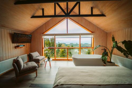 a bedroom with a large window and a bath tub at Tungulú - Hotel Boutique & Cabañas in Puerto Montt
