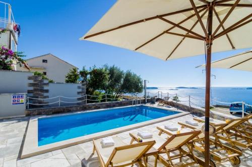 a swimming pool with chairs and an umbrella at Apartment LaVilla in Mlini