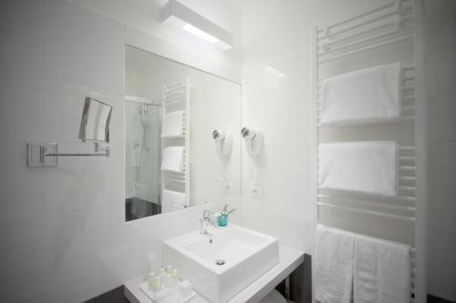 a white bathroom with a sink and a mirror at Hotel Luise in Riva del Garda