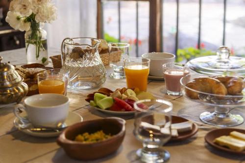 a table with breakfast foods and glasses of orange juice at Los Arcabuceros Casa Hotel Boutique in Tilcara