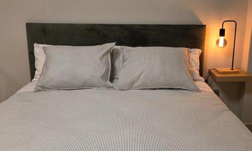 a bed with white pillows and a black headboard at Apartamentos Monte Hernanz in Riaza
