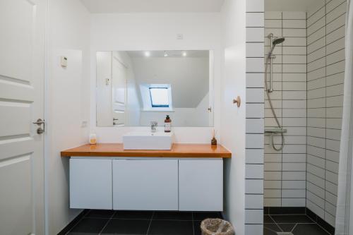 ein Badezimmer mit einem weißen Waschbecken und einem Spiegel in der Unterkunft Aroma Guesthouse in Ærøskøbing