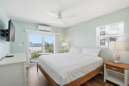 a white bedroom with a bed and a balcony at Windward Passage in Fort Myers Beach
