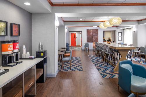 a restaurant with a bar with chairs and a table at Newly Renovated Hampton Inn Omaha West Lakeside in Omaha