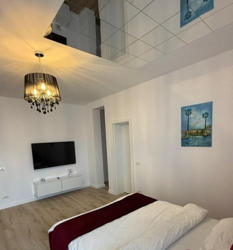 a bedroom with a bed and a tv and a chandelier at VISAJ Jacuzzi Romantic in Timişoara