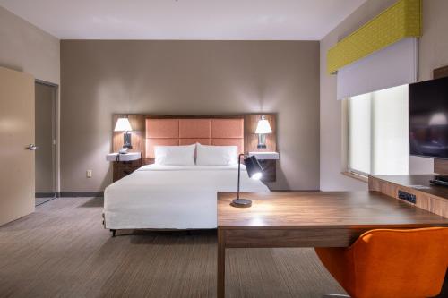 a hotel room with a bed and a desk with a table at Newly Renovated Hampton Inn Omaha West Lakeside in Lane