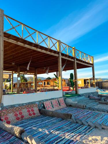a building with a roof with pillows on the ground at Jazz Nuwibaa Camp in Wāsiţ