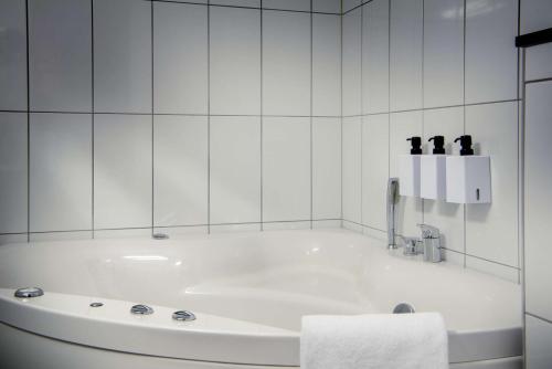 a white bath tub in a white tiled bathroom at Scandic Luleå in Luleå
