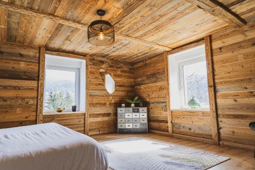 a bedroom with wooden walls and a bed and two windows at La Charbonnière, grand gîte haut-de-gamme avec jacuzzi et sauna in Gérardmer