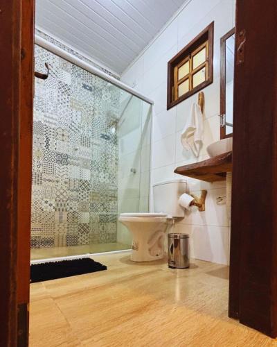 a bathroom with a toilet and a glass shower at Pousada Jardim da Vida in Palmeiras