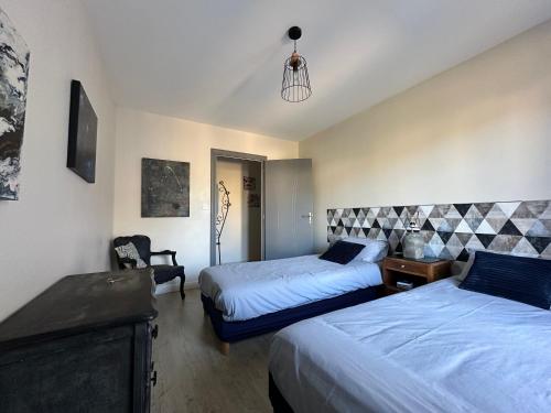 a bedroom with two beds and a chair at L Ecrin d Anabelle in Saint-Georges-lès-Baillargeaux