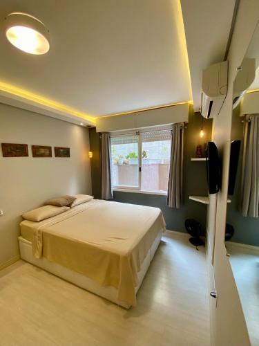 a bedroom with a large bed and a television at Garden Moinhos de Vento in Porto Alegre
