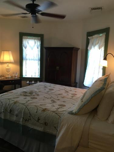 a bedroom with a bed with a ceiling fan and two windows at Parsonage Inn Bed and Breakfast in Saint Michaels