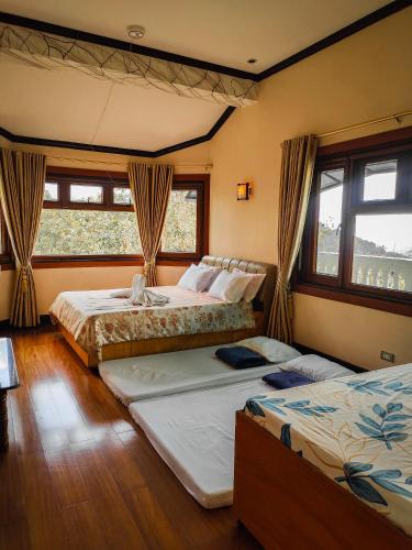 two beds in a room with windows at White House Benguet in Sablan