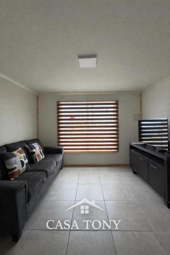a living room with a couch and a large window at Casa Tony Natales in Puerto Natales