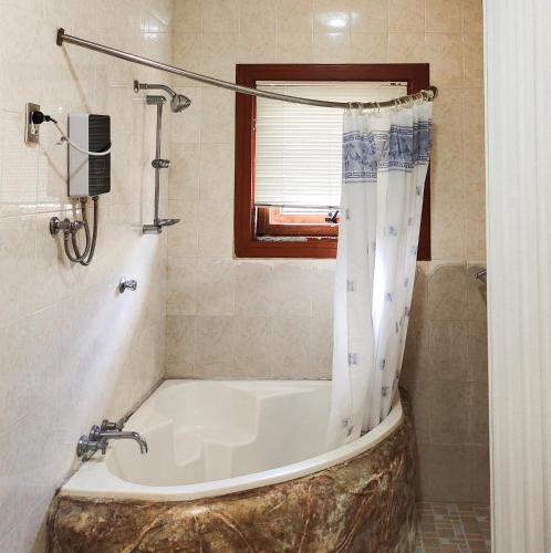 a bathroom with a bath tub with a shower curtain at White House Benguet in Sablan
