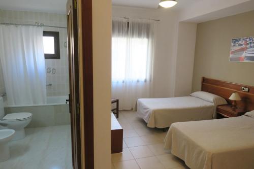 a hotel room with two beds and a bathroom at Hotel Beri in Llança