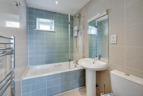 a blue tiled bathroom with a sink and a bath tub at 2 Bed in Brixham oc-bc157 in Brixham