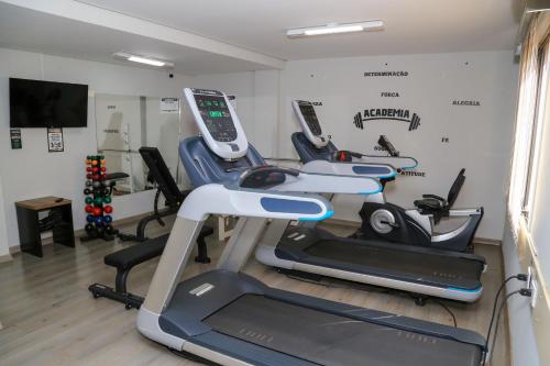 a gym with several cardio machines in a room at Class Hotel Guaxupé in Guaxupé