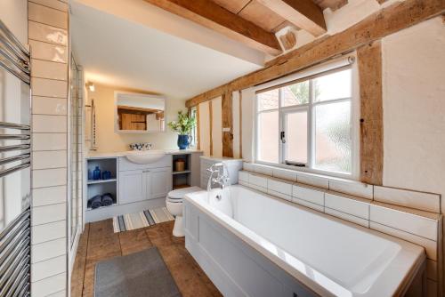a bathroom with a tub and a toilet and a window at 2 Bed in Saxtead oc-pera in Saxtead