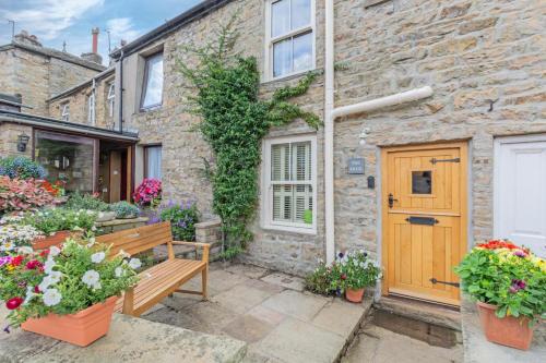 a wooden bench in front of a brick house with flowers at 2 Bed in Hawes oc-ds042a in Hawes