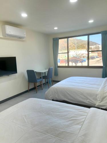 a hotel room with two beds and a tv and a table at Travel Island B&B in Beigan