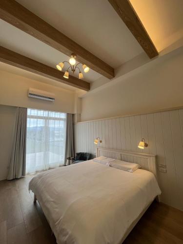 a bedroom with a large white bed and a window at 蘇西好日子別墅 in Sanxing